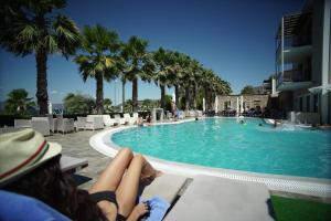 a woman laying on a bench next to a swimming pool at Valis Resort Hotel in Volos
