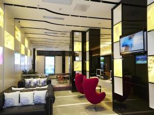 a living room with a couch and red chairs at Lavande Hotel Wuhan Huanghelou Branch in Wuhan