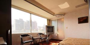 a bedroom with a bed and two chairs and a television at Broadway Hotel in Taichung