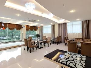 a dining room with tables and chairs and windows at GreenTree Inn Taizhou Gaogang District Business Hotel 