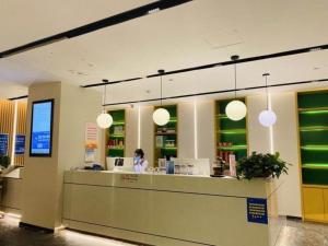 a woman standing at a counter in a store at GreenTree Inn Lianyungang Suning Square Hualian Mantion Hotel in Lianyungang