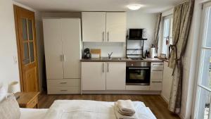 una cocina con armarios blancos y una cama en una habitación en Gästehaus am Plönlein, en Rothenburg ob der Tauber