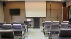 a classroom with tables and chairs and a projection screen at Shantou Grandtide Hotel in Shantou