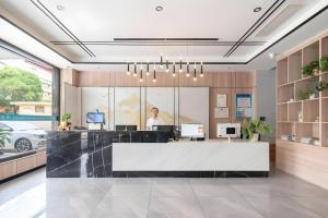 a woman is standing behind a reception desk in an office at GreenTree Inn HanZhong Railway Station Beiyihuan Road Express Hotel in Hanzhong