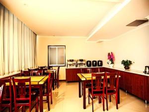 a dining room with wooden tables and red chairs at GreenTree Inn Xinjiang Uygur Autonomous Region Korla Bazhou Bus Terminal Beishan Road Express Hotel in Korla