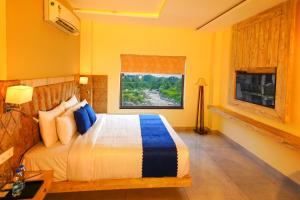 a bedroom with a bed and a television in it at Aachman River Valley Resort by Naina Staycation in Dharmsala