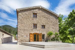 un gran edificio de piedra con puerta de madera en Alberg La Sala, en La Pobla de Lillet