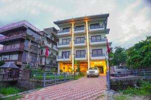 a building with a car parked in front of it at Aachman River Valley Resort by Naina Staycation in Dharmsala