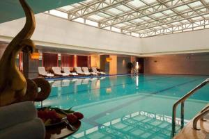 a large swimming pool in a hotel with a plate of fruit at New Century Grand Hotel Lishui Huaqiao in Lishui