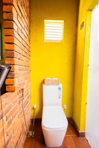 une salle de bains avec des toilettes blanches dans un mur jaune dans l'établissement Cinnamon Cottage Near Colombo Intl Airport, à Madampella Ihala