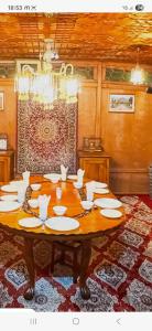 una mesa de comedor con platos blancos. en Houseboat New Golden Fleece, en Srinagar