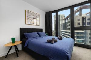 Un dormitorio con una cama azul y una gran ventana. en Modern Southbank Apartment 2BR with Pool & Sauna, en Melbourne