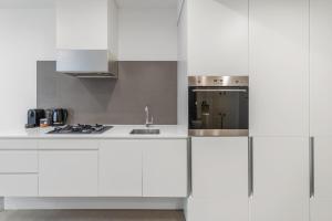 Una cocina blanca con gabinetes blancos y un fregadero. en Modern Southbank Apartment 2BR with Pool & Sauna, en Melbourne