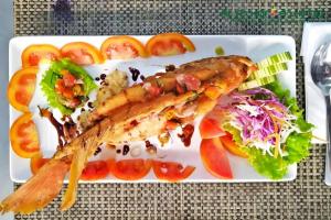 a plate of food with fish and salad on it at AZHIMA Resort and Convention in Solo