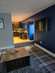 a living room with a table and a blue wall at The Tearoom Tarbet in Tarbet