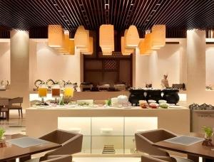 a restaurant with tables and chairs and pendant lights at Ramada Plaza by Wyndham Chuzhou in Chuzhou