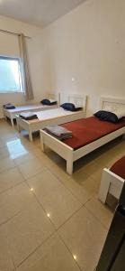 a room with three beds in a room with a window at Sheeva Backpacker Hostel in Abu Dhabi