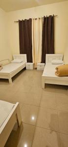 a room with three beds and a window with curtains at Sheeva Backpacker Hostel in Abu Dhabi