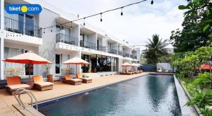 a hotel with a swimming pool with chairs and umbrellas at Double G Resort Anyer in Babagan