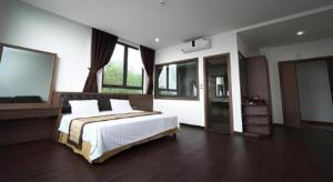 a bedroom with a large bed with white sheets and windows at LAKESIDE DAILAI HOTEL in Ngọc Quang