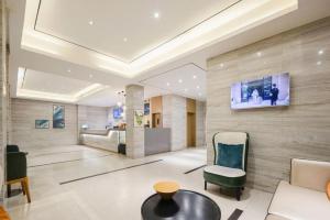WuzhouにあるCity Comfort Inn Wuzhou Wangcheng Squareのソファと壁掛けテレビのあるロビー