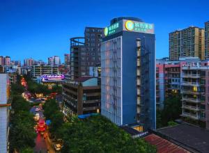 WuzhouにあるCity Comfort Inn Wuzhou Wangcheng Squareの街中の看板が掲げられた高層ビル