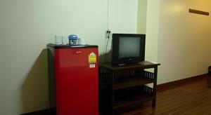 a red refrigerator next to a tv and a table at Erawan Place in Mae Sot