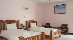 two beds in a room with two chairs at Erawan Place in Mae Sot