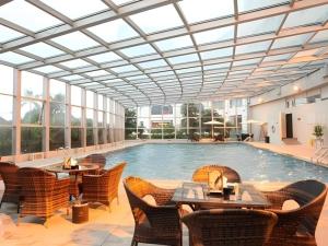 a swimming pool with tables and chairs in a building at Putian Haiyuan International Hotel in Putian