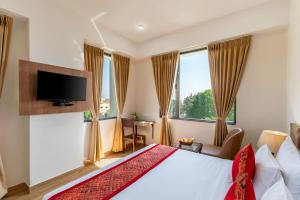 a hotel room with a bed and a flat screen tv at De Glance Udaipur in Udaipur