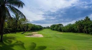a lush green golf course with a palm tree at Waterford Valley Chiangrai Golf Course and Resort in Chiang Rai