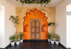 an orange wall with a door and potted plants at De Glance Udaipur in Udaipur