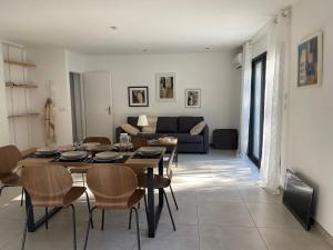 a dining room and living room with a table and chairs at Maison Romarin in Le Boulou