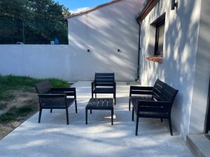 four black chairs and a bench on a patio at Maison Romarin in Le Boulou