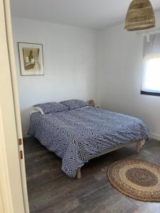 a bed with a blue and white comforter in a bedroom at Maison Romarin in Le Boulou
