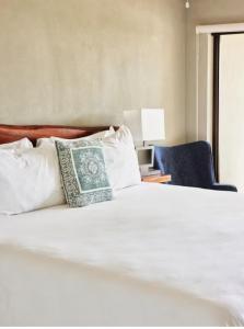 una cama blanca con una almohada y una silla azul en Hotel River hill, en Bashist