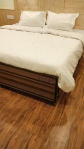 Dos camas con sábanas blancas y almohadas sobre un suelo de madera. en Hotel River hill, en Bashist