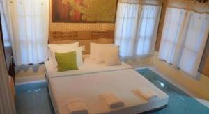 a bedroom with a white bed with green pillows and windows at Pangsarapee Resort in Mae Sai