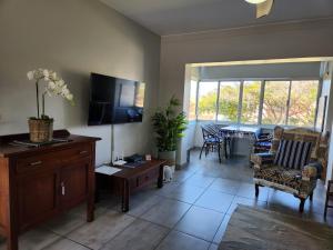 a living room with a tv and a table with chairs at Dolfyn201 La Mer in Hartenbos