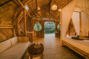 a bedroom with a bed and a table in a room at Asvara Eco Bali Bamboo House in Sidemen