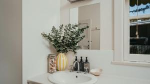a bathroom sink with a vase of flowers and wine bottles at The Marlin in Currarong +30 photos