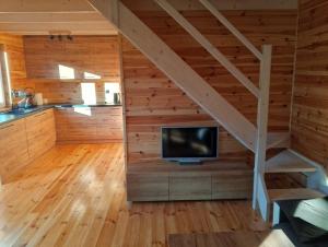 a living room with a staircase and a tv in a cabin at Miodowa cisza in Szafarnia