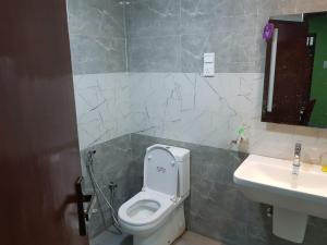 a bathroom with a white toilet and a sink at Seethevi Hotels in Batticaloa