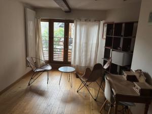 a living room with chairs and a table and a window at Chambre suite de L'argentier in Noyarey