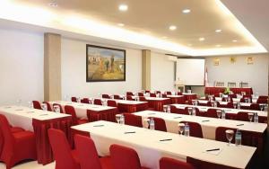 a conference room with tables and red chairs at Mataram Square Hotel in Gili Trawangan