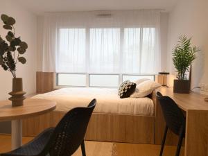 a bedroom with a bed and two chairs and a table at Sweetly Saclay Gif-sur-Yvette in Gif-sur-Yvette