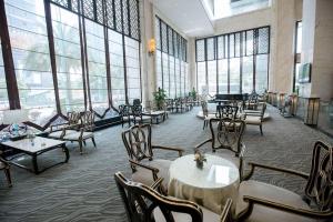 a restaurant with tables and chairs and large windows at Fortune International Hotel in Xiawutun