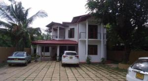 a white house with two cars parked in front of it at Seven Flowers Hotel in Anuradhapura +15 photos