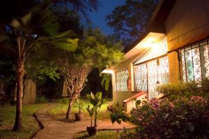 a house with a garden with trees and a pathway at Boma Banda Diani - Kaskazi Cottage in Diani Beach
