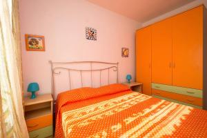 1 dormitorio con 1 cama con colcha de color naranja en I Tre Bagli, en San Vito lo Capo